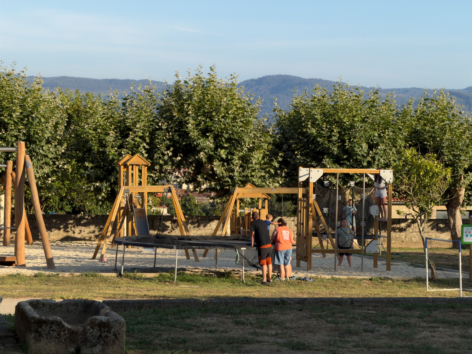 Familias en el parque infantil con columpios, red de escalada y cama elástica de Ledicia Camper Park
